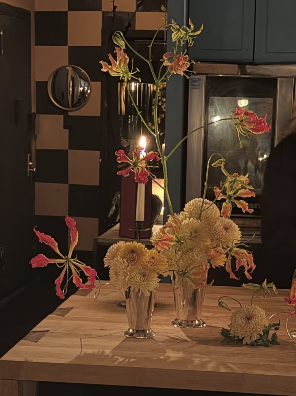 Gloriosa lilies on tall stems rising from silver julep cups of chrysanthemums, by candlelight (2 of 3)